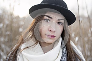 Portrait of beauty woman with big brown eyes, and bowler hat on, in winter scenery