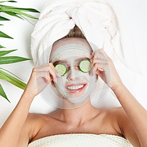 Portrait of beauty woman laying with towel on the head, cucumber on her eyes, facial mask. Spa therapy. Relax.