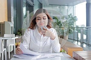 Portrait of beauty young Asian business woman analyzing paperwork or charts on the desk in office