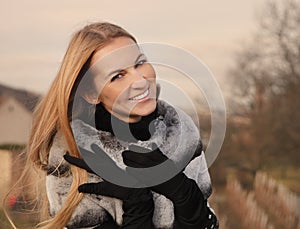 Portrait of the beauty young smiling blond woman wearing fur coat