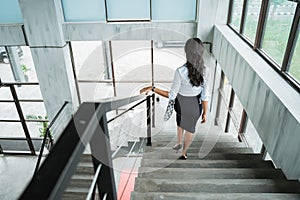 Portrait from behind of businesswoman walking down stairs alone