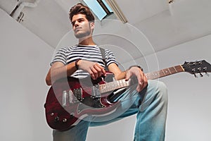 Portrait from below upward of young guitarist looking away