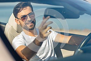 Portrait of berded man looking in the car mirror