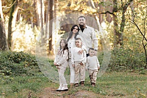 Portrait of big family outdoors. Young Stylish bearded dad with little son on shoulder, beautiful brunette mom, child