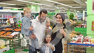 Portrait of a big happy family in the supermarket, they show their thumb up.