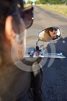 Portrait of a biker girl in the motorcycle mirror reflection