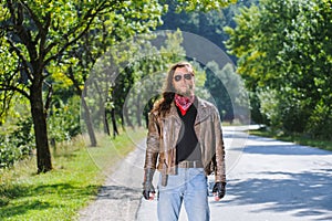 Portrait of biker man with beard standing on the road