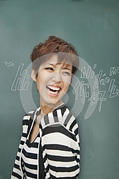 Portrait of bilingual woman laughing in front of blackboard