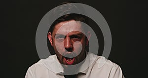 Portrait of a bipolar patient against black studio copy space background. Mentally ill man shouting and laughing