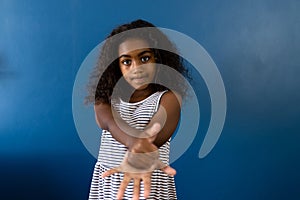 Portrait of biracial girl using sign language with hand on blue background