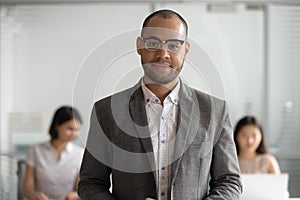 Portrait of biracial male employee in glasses posing at workplace