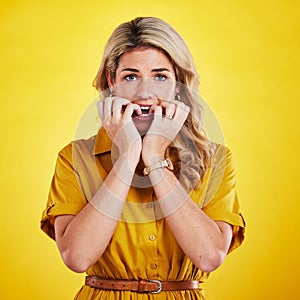 Portrait, biting nails and woman in studio with anxiety, nervous and afraid against yellow background. Panic, fear and