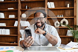 Portrait of black entrepreneur in office watching at phone while working
