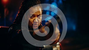 Portrait of black female police officer aiming gun at criminal, orders to drop the weapon and stop