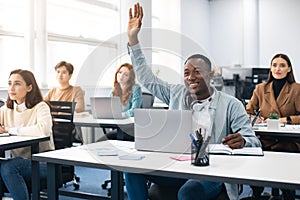 Portrait of black guy student raising hand at classroom