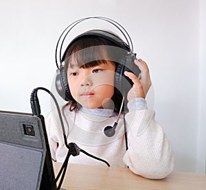 Portrait of a black haired girl in a white shirt. Enjoying listening to music in the room.