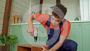 Portrait of black handyman assembling DIY furniture with electric screwdriver