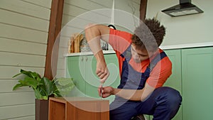 Portrait of black handyman repairing furniture with screwdriver indoors