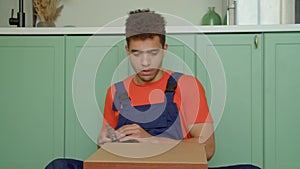 Portrait of black male DIYer with hammer installing bedside table rear panel