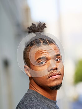 Portrait, black man and cool or funky hairstyle in city with topknot and braided hair for barbershop. Creative photo
