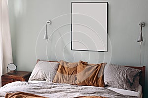 Portrait black picture frame mockup and silver lamps on sage green wall. Bedroom view. Grey linen and rusty muslin