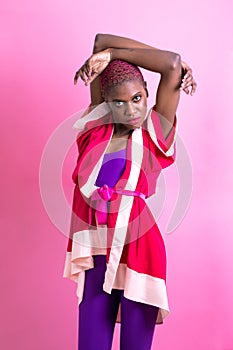 Portrait of a black short haired woman in front of a pink background