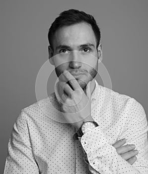 Portrait in black and white of a handsome young man. Elegant pose with white dots shirt. Serious expression.