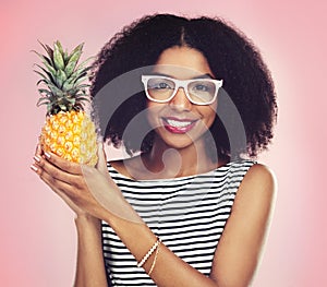 Portrait, black woman and pineapple with fashion, studio and smile on pink background. Face, fruit and summer clothing