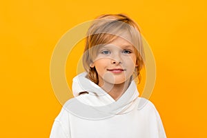 Portrait of blond boy grimacing on yellow studio background close-up