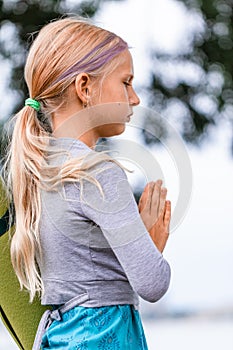 Portrait of Blond caucasian girl in namaste. girl hands in namaste gesture outdoor summer day. yoga, mindfulness, harmony concept