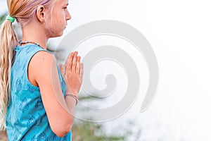 Portrait of Blond caucasian girl in namaste. girl hands in namaste gesture outdoor summer day. yoga, mindfulness, harmony concept