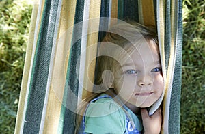 Portrait of blond child girl, relaxing on a colorful hammock