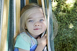 Portrait of blond child girl, relaxing on a colorful hammock