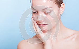 Portrait blond girl in facial mask on blue. Beauty and skin care.