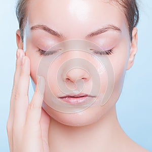 Portrait blond girl in facial mask on blue. Beauty and skin care.