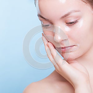 Portrait blond girl in facial mask on blue. Beauty and skin care.