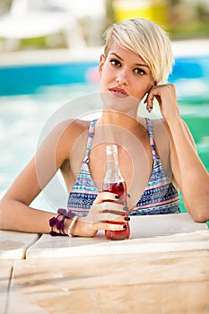 Portrait of blond girl in piscine with refreshing drink