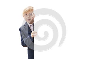 Portrait of blond little boy with white blank isolated on white background. Boy with glasses and school uniform peeking out from