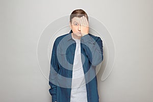 Portrait of blond mature man covering half of his face with hand