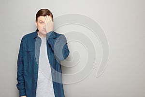 Portrait of blond mature man covering half of his face with hand