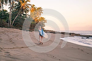 Portrait of blond surfer girl with white surf board in blue ocean pictured from the water in Encuentro beach photo