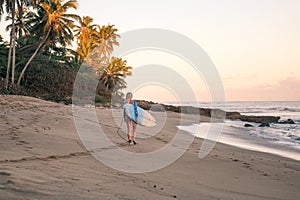 Portrait of blond surfer girl with white surf board in blue ocean pictured from the water in Encuentro beach photo