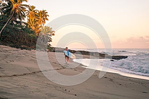 Portrait of blond surfer girl with white surf board in blue ocean pictured from the water in Encuentro beach photo