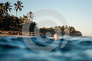 Portrait of blond surfer girl on white surf board in blue ocean pictured from the water in Encuentro beach photo