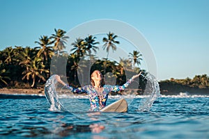 Portrait of blond surfer girl on white surf board in blue ocean pictured from the water in Encuentro beach photo