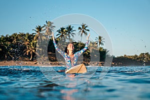 Portrait of blond surfer girl on white surf board in blue ocean pictured from the water in Encuentro beach photo