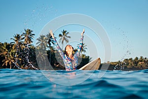 Portrait of blond surfer girl on white surf board in blue ocean pictured from the water in Encuentro beach photo