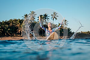 Portrait of blond surfer girl on white surf board in blue ocean pictured from the water in Encuentro beach photo