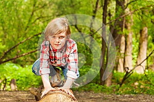 Portrait of blond young boy standing on a log