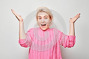 Portrait blond young woman happy face smiling joyfully with raised palms and shocked open mouth